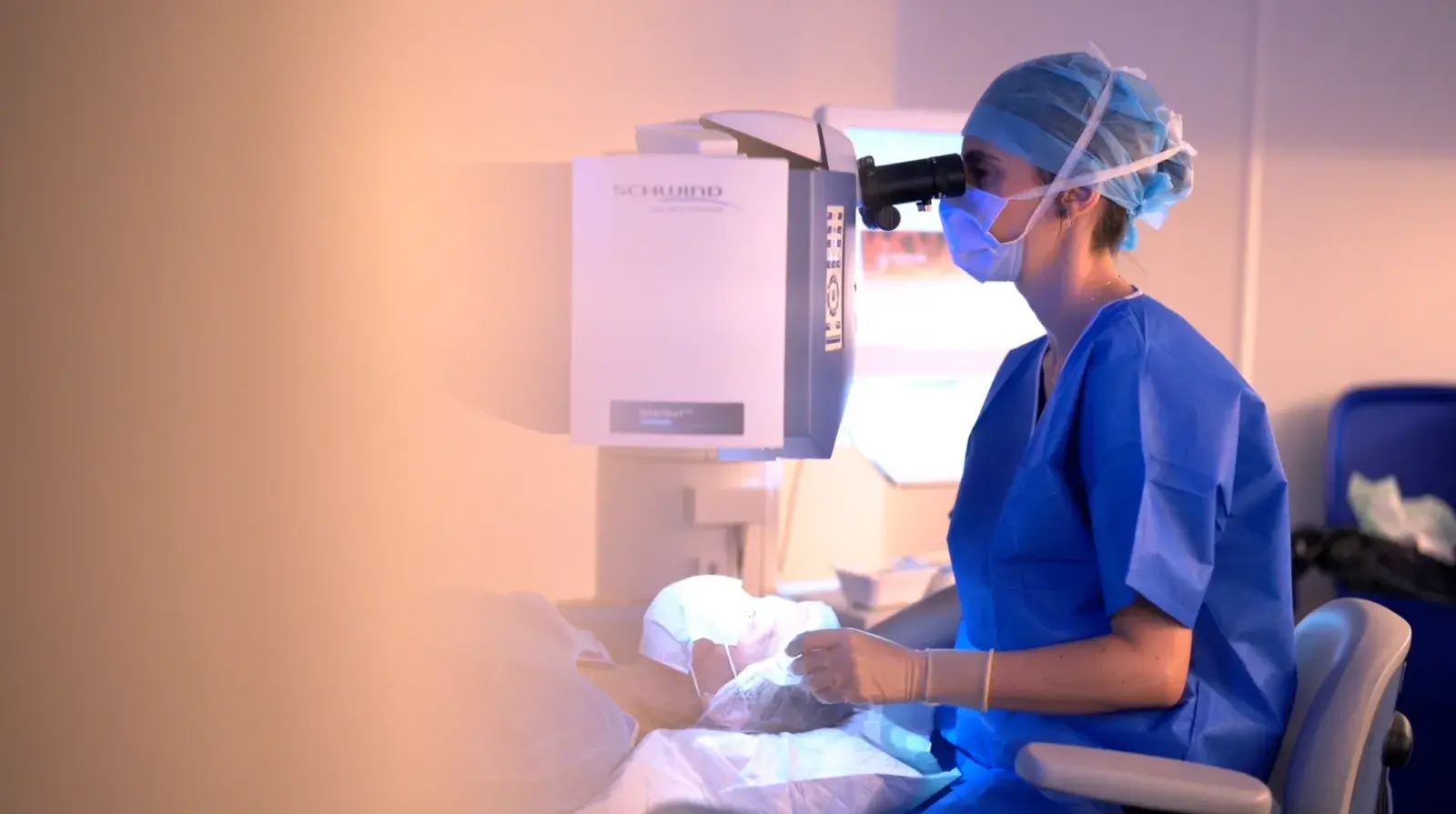 Une chirurgienne regarde dans l'oculaire du laser pendant une intervention de chirurgie réfractive.