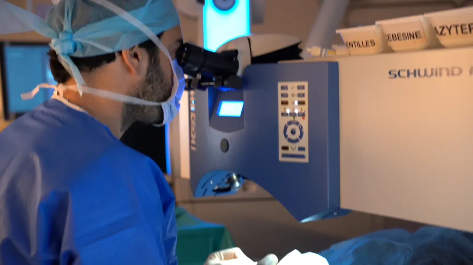 Un chirurgien en tenue de bloc regarde dans l'oculaire du laser de chirurgie réfractive.